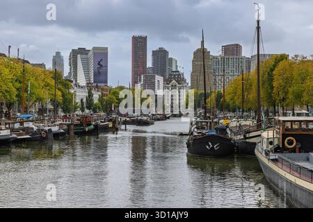 Le port intérieur historique de Haringvliet à Rotterdam, avec des voiliers et des bateaux traditionnels, avec un paysage urbain de bâtiments sous un nuage Banque D'Images