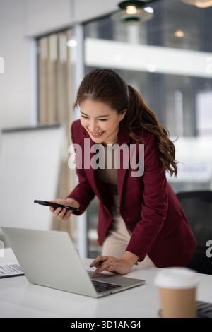 Femme d'affaires asiatique professionnelle s'engage dans des tâches immobilières en utilisant la technologie moderne pour se connecter avec les clients et gérer les annonces immobilières avec un jogging Banque D'Images