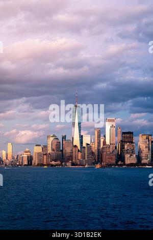 Vue d'un paysage urbain vibrant illuminé par la douce lueur du soleil couchant, contrastant avec le bleu profond de l'eau, New York, New York, Unite Banque D'Images