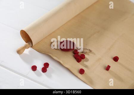 Rouleau de vieux papier parchemin avec sceau et perles de cire sur la table en bois blanc, gros plan Banque D'Images
