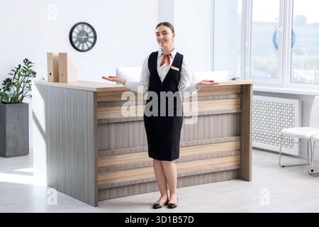 Heureux réceptionniste accueillant près de la réception à l'intérieur Banque D'Images