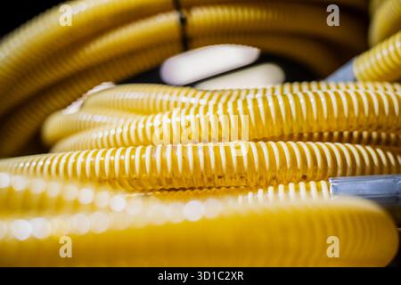 Vue rapprochée des tuyaux en plastique ondulé jaune enroulés montrant la texture des tuyaux flexibles utilisés dans l'installation de conduites de gaz, la tuyauterie industrielle et la construction Banque D'Images