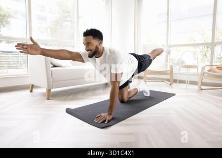 Bel homme africain fait des asanas de yoga dans le salon Banque D'Images