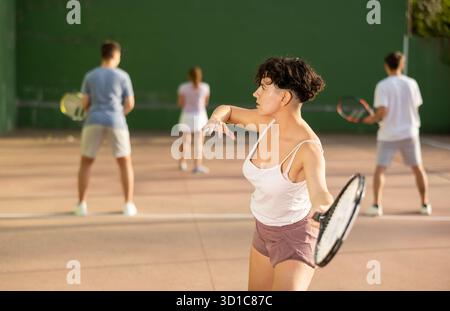 Femme servant le ballon pendant le jeu frontenis à l'extérieur Banque D'Images