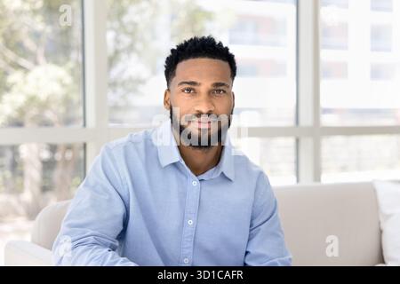 Homme africain sérieux posant assis dans un salon moderne Banque D'Images