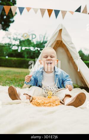 Un tout-petit joyeux célèbre son anniversaire tant attendu avec un gâteau coloré et des décorations vibrantes, entouré de famille et d'amis créant chéris Banque D'Images