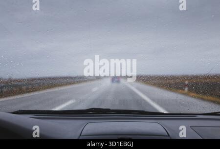 Voiture conduisant par mauvais temps pluie pare-brise laisse tomber l'eau sur la route Banque D'Images