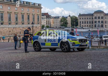 Stockholm, Suède - 08.05.2025 : deux policiers avec des fusils et une voiture de police à Gamla Stan, Stockholm, Suède Banque D'Images