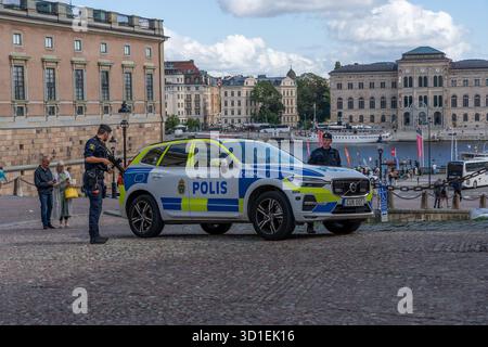 Stockholm, Suède - 08.05.2025 : deux policiers avec des fusils et une voiture de police à Gamla Stan, Stockholm, Suède Banque D'Images