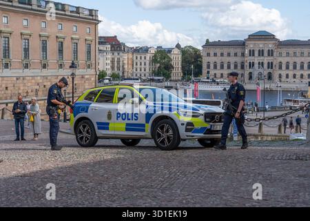 Stockholm, Suède - 08.05.2025 : deux policiers avec des fusils et une voiture de police à Gamla Stan, Stockholm, Suède Banque D'Images