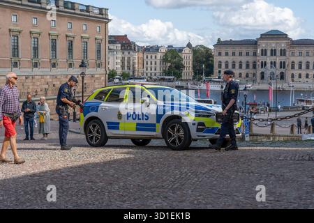Stockholm, Suède - 08.05.2025 : deux policiers avec des fusils et une voiture de police à Gamla Stan, Stockholm, Suède Banque D'Images