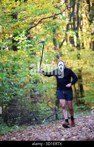Halloween Ghostface Runner avec Scythe sur un sentier forestier d'automne Banque D'Images