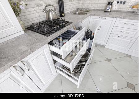 Intérieur de la cuisine moderne en bois blanc dans la maison de luxe, certains tiroirs sont ouverts Banque D'Images