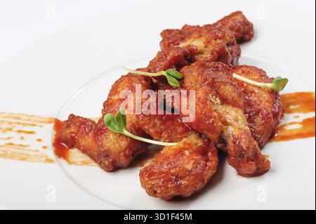 Cuisses de poulet rôties dans une sauce caramel épicée rouge avec des germes de haricots verts dans une assiette blanche Banque D'Images