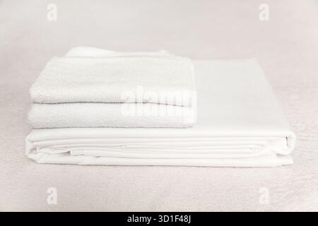 Un ensemble de serviettes blanches fraîchement pliées repose soigneusement sur une surface douce. Les serviettes présentent un aspect net et net, parfait pour un sp. Relaxant Banque D'Images