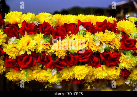 Chrysanthèmes jaune vif et guirlande florale de roses rouges pour la célébration, la décoration et la floraison festive Banque D'Images