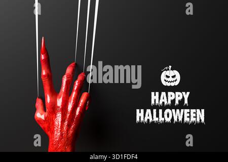 Une main terrifiante, rouge, sanglante, maléfique laissant des marques de griffes sur un mur noir. Joyeux concept d'Halloween. Banque D'Images