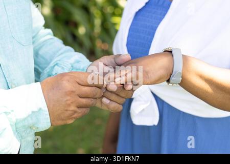 Couple senior échangeant des anneaux à l'extérieur, célébrant l'amour et l'engagement ensemble. Romance, personnes âgées, cérémonie, mariage, affection, célébration || autorisation du modèle Banque D'Images