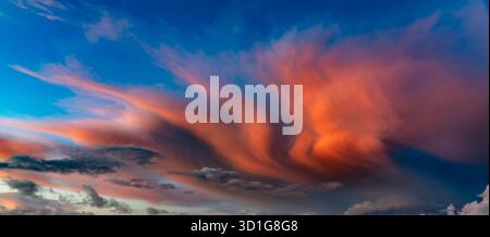 De spectaculaires nuages ardents balayent le ciel nocturne dans des tons orange et rose vifs Banque D'Images