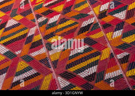 Tapis arabe vif tissé à la main avec motifs répétitifs, rouge vif, jaune et blanc, texture photo de fond Banque D'Images