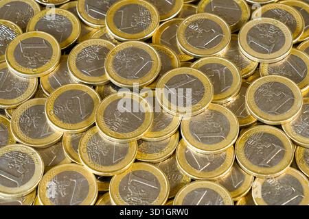 Pièces d'un euro, dispersées et empilées, représentant la monnaie européenne, l'économie, l'épargne, les services bancaires, et la stabilité financière dans la zone euro Banque D'Images
