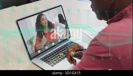 Homme senior dans le polo rouge prenant des notes au bureau, avec l'usine de stylo de cahier de tableau d'ordinateur portable Banque D'Images