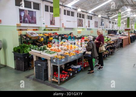 Les gens qui achètent des fruits et légumes à un étal dans le marché couvert de la ville portugaise de Tomar Portugal Banque D'Images