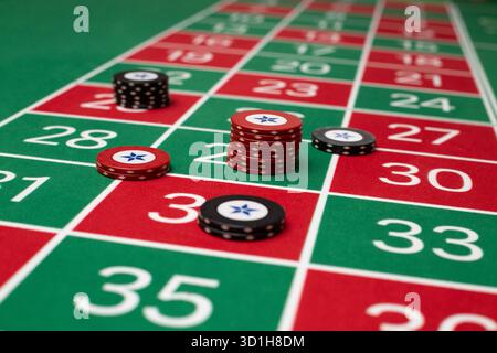 JEU, TABLE DE ROULETTE GÉNÉRIQUE, JETONS, STRATÉGIE : une table de roulette classique de joueur POV avec jetons disposés dans une stratégie de Paris commune dans un casino en direct. Banque D'Images