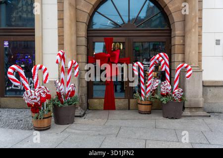 Entrée festive du magasin de Noël décorée de cannes de bonbons géantes et arc en ruban rouge dans des tonneaux en bois avec de la verdure. Shopping de vacances, vente au détail de Banque D'Images