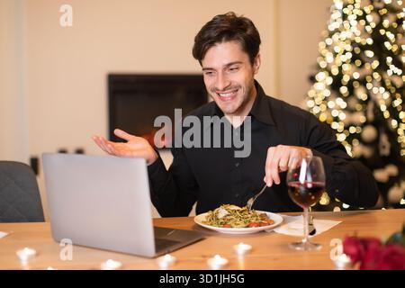 L'homme aime dîner tout en discutant vidéo dans une chambre confortable décorée pour les vacances Banque D'Images