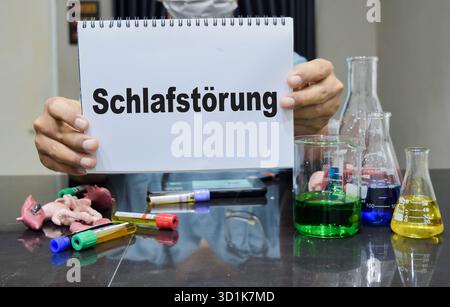 Un technicien de laboratoire souligne schlafstorung en allemand cela signifie trouble du sommeil sur un livre. concept de recherche scientifique Banque D'Images