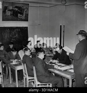 URSS, RSS d'Ukraine, années 1970 Sloviansk, oblast de Donetsk. Une salle de classe à l'usine d'armature et d'isolation (AIZ) ou à un collège technique connexe (Tekhnikum). Une leçon dans une spécialité technique est en cours. Un groupe d'étudiants (hommes adultes et jeunes, ouvriers d'usine) s'assoient aux bureaux. Sur les tables se trouvent des dessins techniques, des composants et des outils de mesure (étriers). Les tolérances techniques (3pm0.2) sont inscrites sur le tableau. Un enseignant dirige la classe. Cette photo d'archive montre le système de formation professionnelle et d'amélioration des qualifications dans une usine soviétique. Banque D'Images
