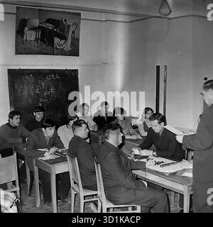URSS, RSS d'Ukraine, années 1970 Sloviansk, oblast de Donetsk. Une salle de classe à l'usine d'armature et d'isolation (AIZ) ou à un collège technique connexe (Tekhnikum). Une leçon dans une spécialité technique est en cours. Un groupe d'étudiants (hommes adultes et jeunes, ouvriers d'usine) s'assoient aux bureaux. Sur les tables se trouvent des dessins techniques, des composants et des outils de mesure (étriers). Les tolérances techniques (3pm0.2) sont inscrites sur le tableau. Un enseignant dirige la classe. Cette photo d'archive montre le système de formation professionnelle et d'amélioration des qualifications dans une usine soviétique. Banque D'Images