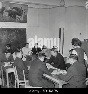 URSS, RSS d'Ukraine, années 1970 Sloviansk, oblast de Donetsk. Une salle de classe à l'usine d'armature et d'isolation (AIZ) ou à un collège technique connexe (Tekhnikum). Une leçon dans une spécialité technique est en cours. Un groupe d'étudiants (hommes adultes et jeunes, ouvriers d'usine) s'assoient aux bureaux. Sur les tables se trouvent des dessins techniques, des composants et des outils de mesure (étriers). Les tolérances techniques (3pm0.2) sont inscrites sur le tableau. Un enseignant dirige la classe. Cette photo d'archive montre le système de formation professionnelle et d'amélioration des qualifications dans une usine soviétique. Banque D'Images