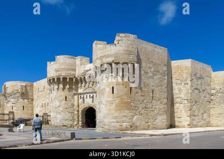 Homme debout près de l'entrée de la Citadelle de Qaitbay alias Fort de Qaitbay, une forteresse historique à Alexandrie, Egypte Banque D'Images