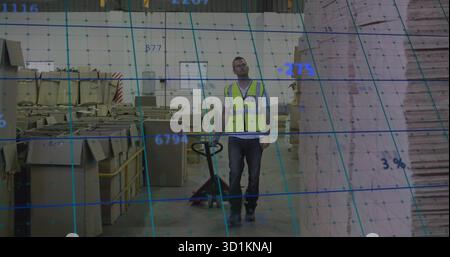 En utilisant le transpalette ouvrier portant le gilet de sécurité déplaçant les palettes à l'entrepôt, avec des boîtes en carton Banque D'Images