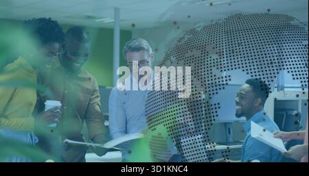 Debout autour de collègues vêtus d'une tenue de bureau examinant des documents dans un bureau ouvert avec une tasse à café Banque D'Images