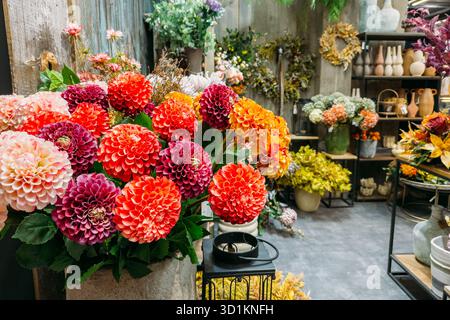 Fleurs de dahlia artificielles aux couleurs vives dans une boutique de fleurs rustiques. Faux botaniques, décoration de détail durable, style floral, esthétique artisanale Banque D'Images