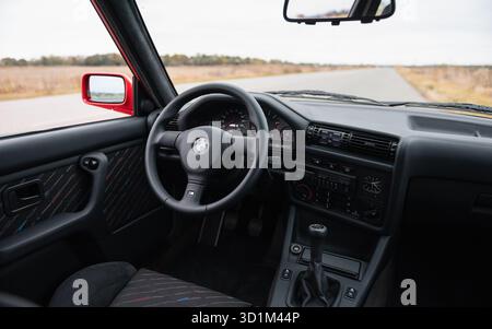 Intérieur BMW des années 1980 avec sièges en cuir noir et tissu. Intérieur de la voiture de sport compacte M3 E30 sur route rurale : panneau avant et volant, tableau de bord. Banque D'Images