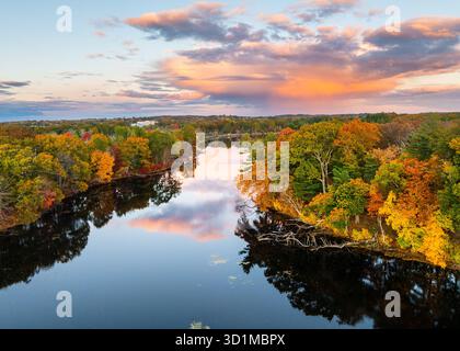 Vue aérienne de Fisk Pond avec un feuillage automnal vibrant, reflétant le coucher de soleil coloré dans ses eaux. Natick, Massachusetts, États-Unis. Banque D'Images