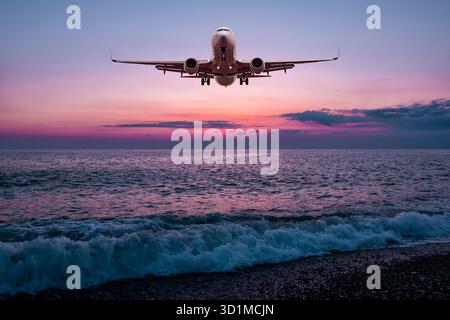 L'avion de passagers atterrit au-dessus de la mer avec pour toile de fond le ciel pittoresque du lever du soleil Banque D'Images