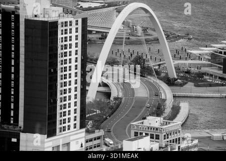 BUSAN, CORÉE DU SUD - 9 OCTOBRE 2025 - L'horizon de la ville de Busan présente une architecture moderne, un pont en arc et une circulation routière animée en noir et blanc Banque D'Images