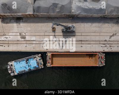 Vue aérienne d'une grue chargeant des matériaux sur des barges, contrastant l'eau sombre avec le béton clair, Berlin, Allemagne. Banque D'Images