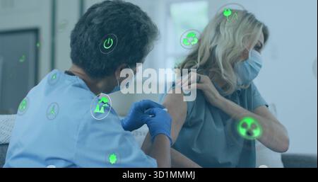 Infirmière portant des gommages bleus donnant un vaccin au patient dans une clinique lumineuse avec seringue et icônes Banque D'Images