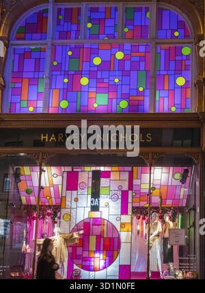 Leeds, Royaume-Uni - 14 décembre 2021 : une femme portant un masque passe devant le grand magasin Harvey Nichols magnifiquement illuminé de Leeds CIT Banque D'Images
