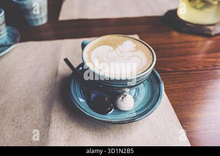 Grande tasse de cappuccino est debout sur le papier artisanal sur la table, POV. Couleur vintage teinte Banque D'Images