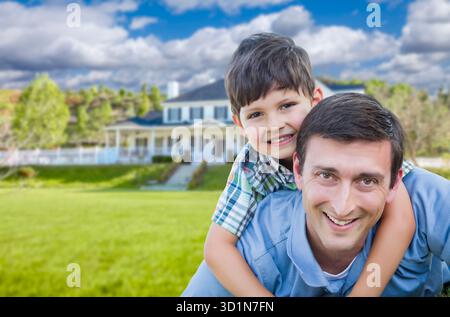 Race mixte Père et fils Piggyback devant la maison Banque D'Images