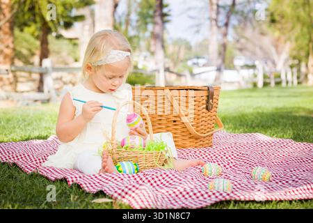 Cute Baby Girl coloriant les oeufs de Pâques sur la couverture de pique-nique Banque D'Images