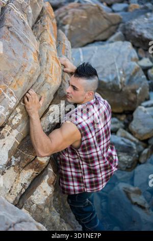 Bel homme grimpant un rocher à la rivière Banque D'Images