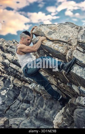 Bel homme grimpant un rocher à la rivière Banque D'Images